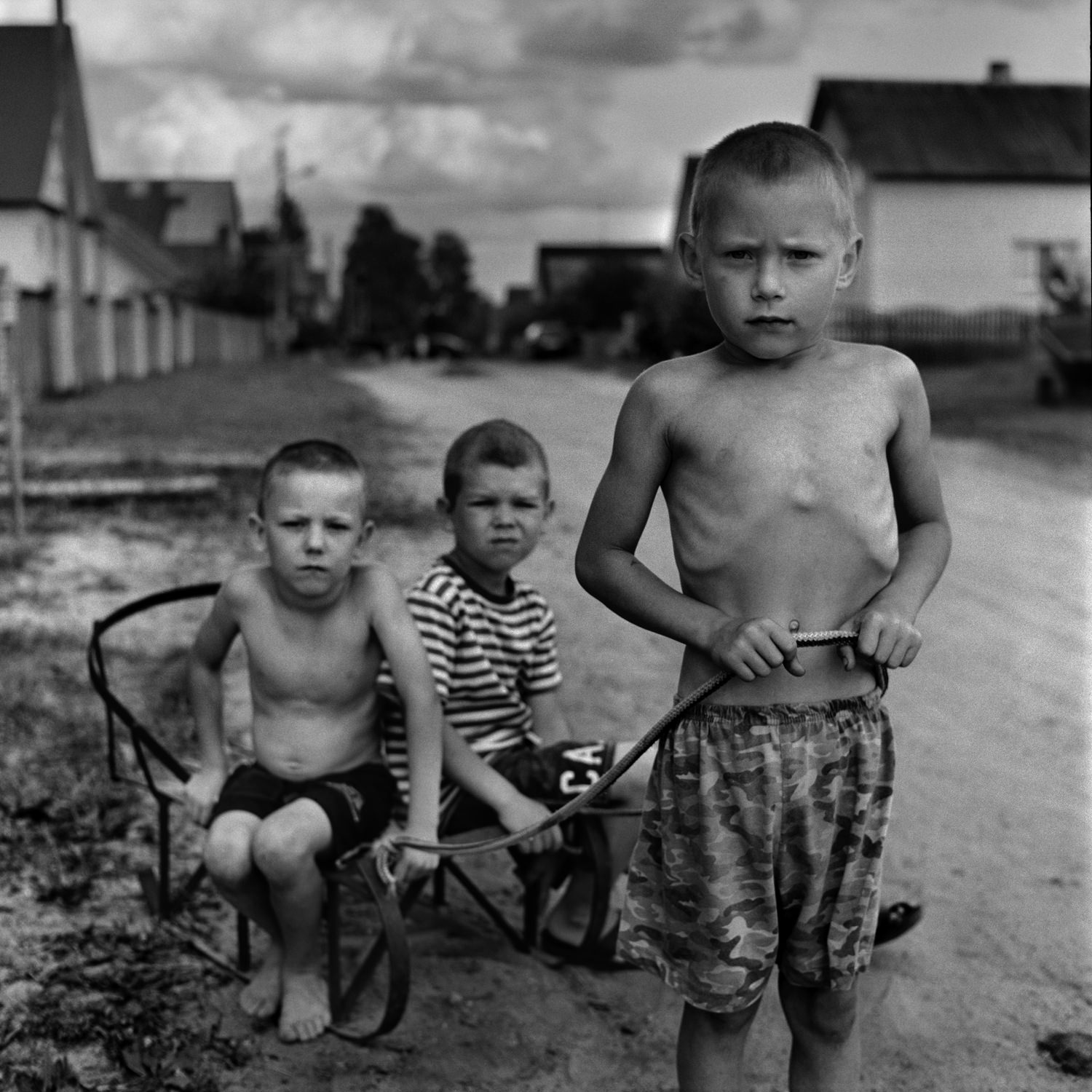 Documentary street portrait of three naked boys on countryside road with sled taken on Bronica SQ-Ai medium format camera and blac-and-white film
