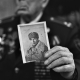 Close-up portrait of old veteran holding war time photo in his hand