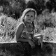 Expressive portrait of a little girl with pigtails and a light dress with her hands on a well with water on a hot summer day taken on black-white film