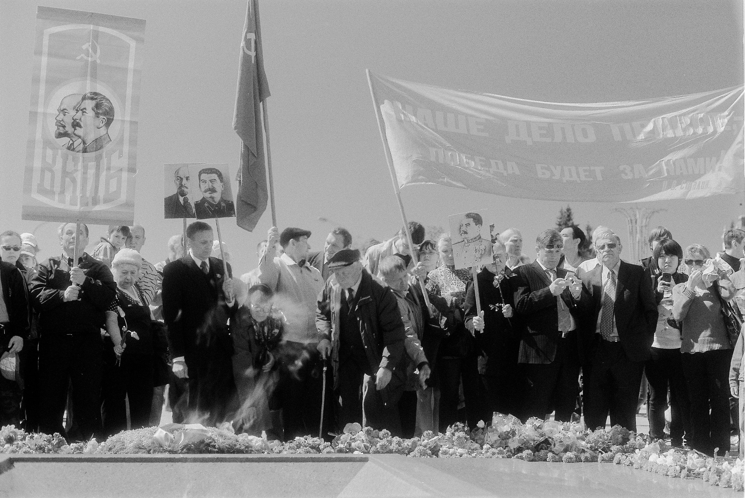 Veterans of the Soviet Army and members of the Communist Party with red flags, St. George ribbons and portraits of Lenin and Stalin lay flowers on the Eternal Flame during the Victory Day celebrations