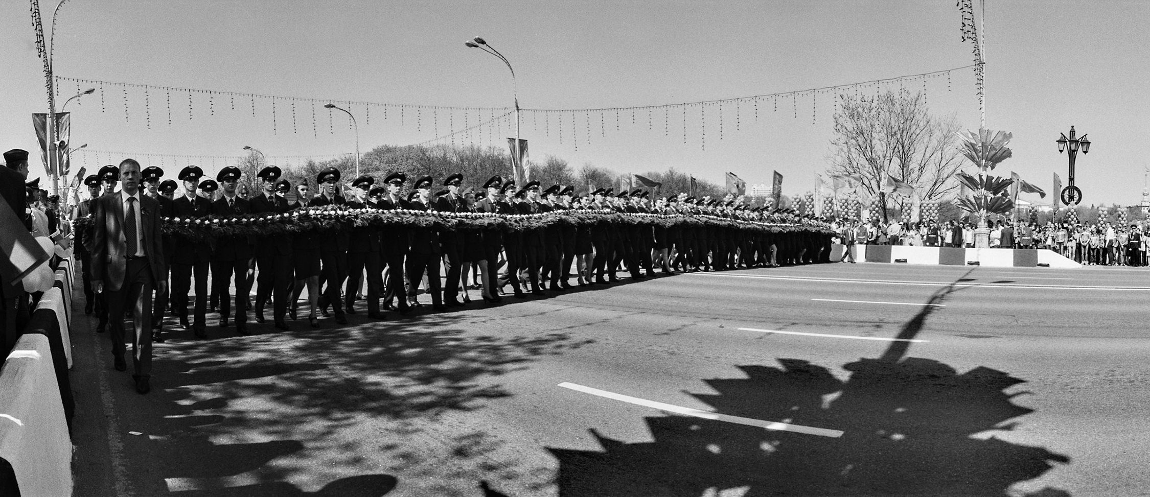 Panoramic black-white street photo of young soldiers carrying flowers along the main boulevard on parade in Minsk, Belarus