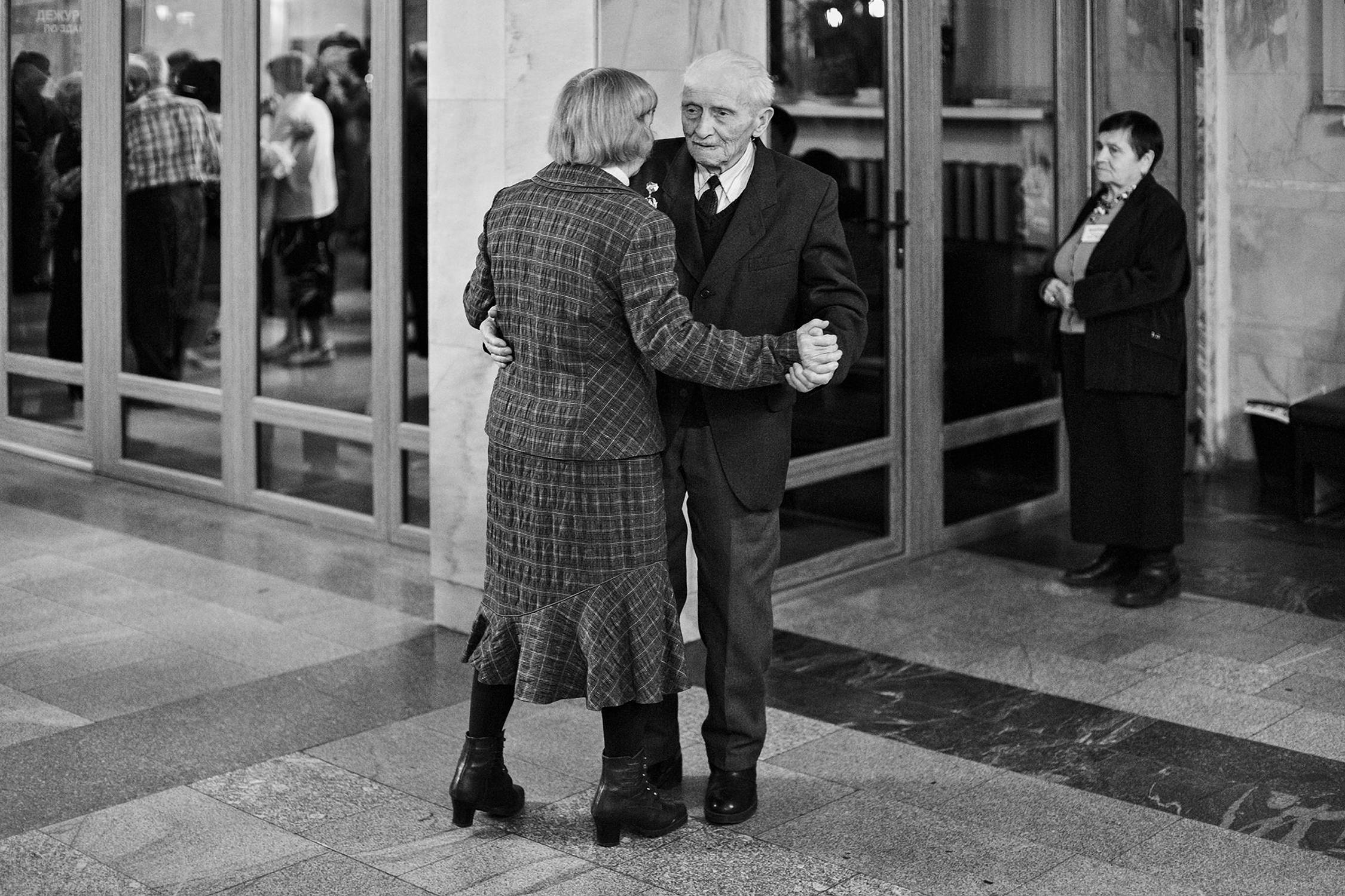 Reportage photo of old married couple dancing in the hall at veterans party in Minsk
